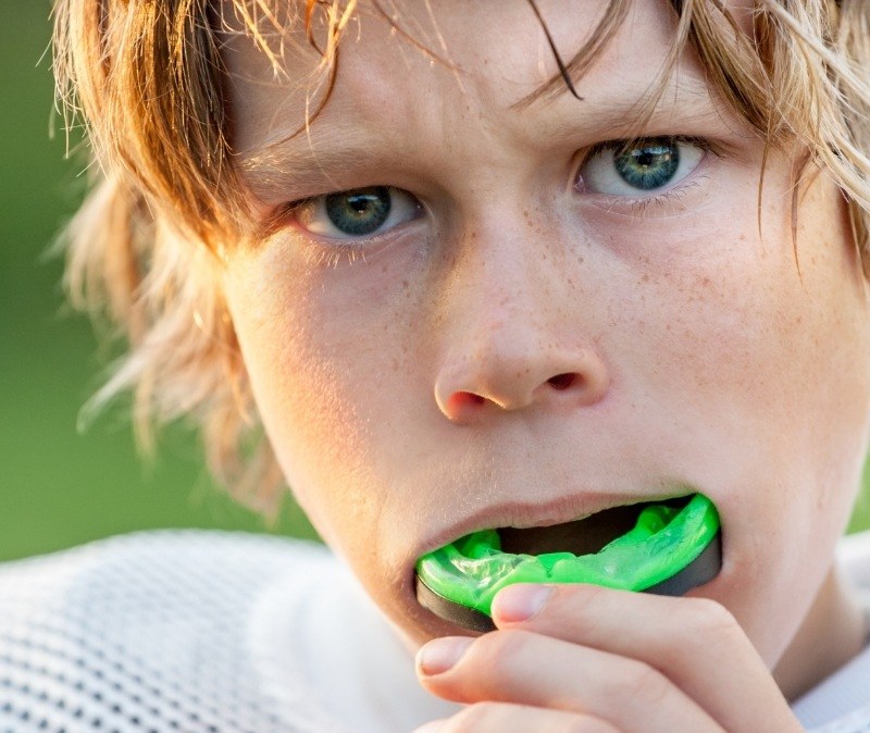 Teen placing a green sports mouthguard