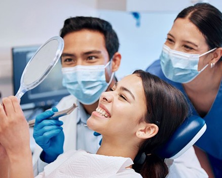 Happy dental patient admiring her teeth in the mirror