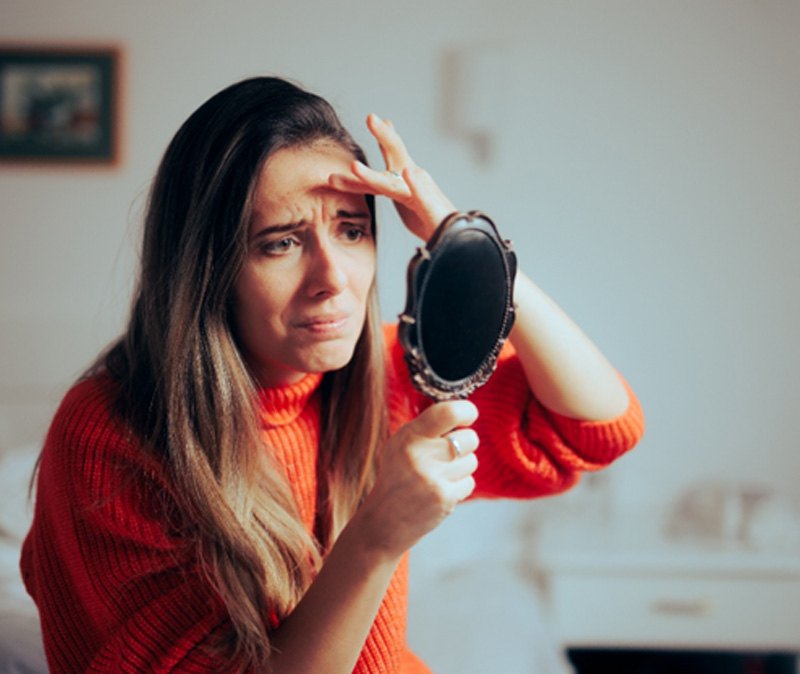 woman looking at her frown lines  