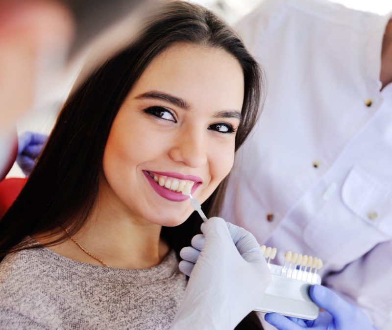 Woman's smile compared with veneers color chart