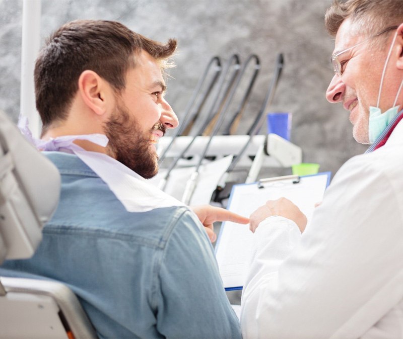 Dentist and patient discussing information on clipboard
