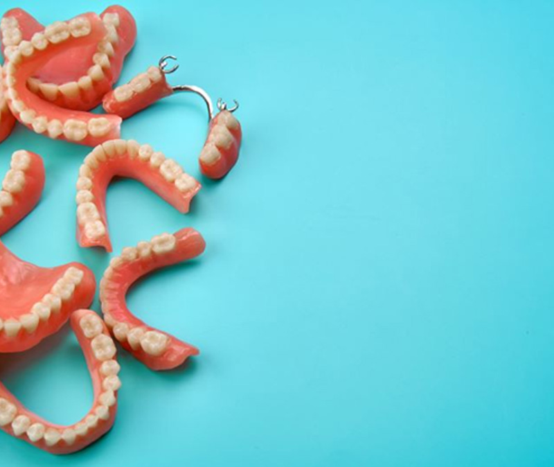Multiple types of dentures pictured against blue background