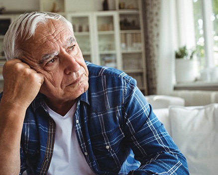 Sad senior man sitting on sofa