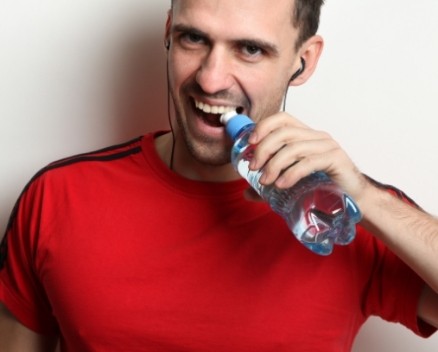 Man using teeth to open a water bottle