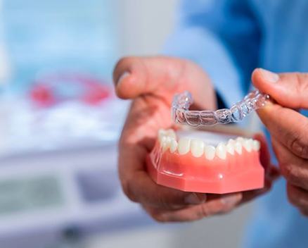 Dentist using model to demonstrate how Invisalign works