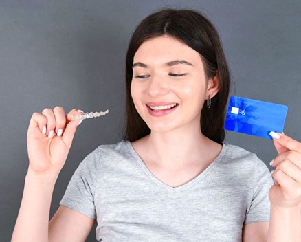 Woman holding payment card and Invisalign aligner