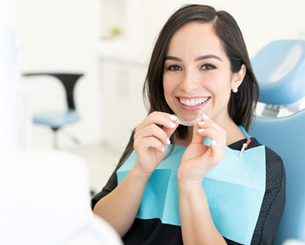 Invisalign patient holding her clear aligner