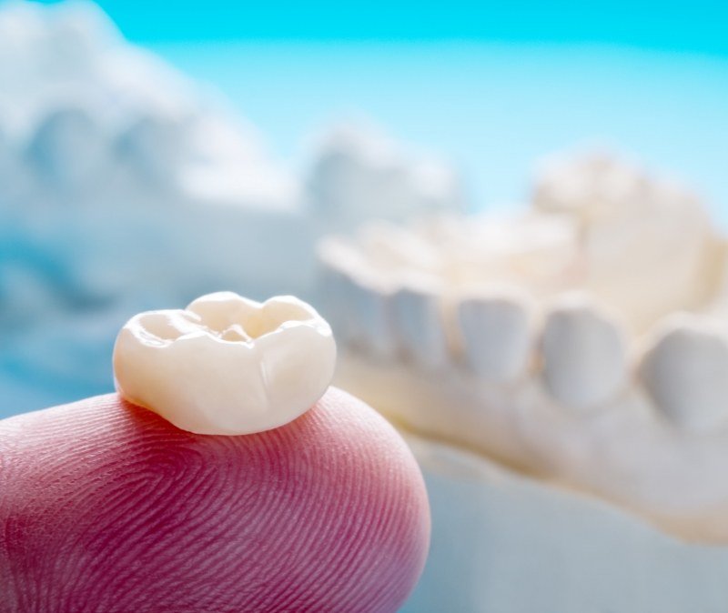 Dental crown on fingertip during restorative dentistry visit