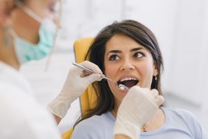 A dentist checking a patient’s mouth for oral cancer.