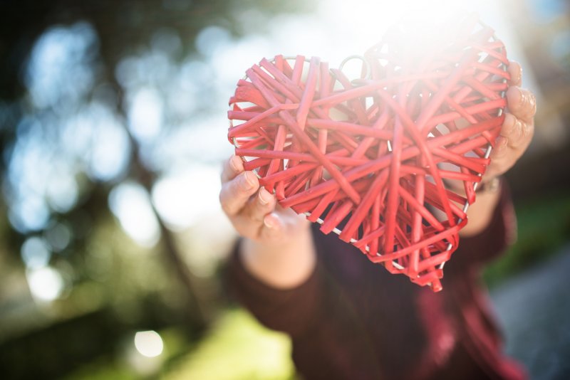 Person holding a cross-stitched heart for American Heart Health Month.