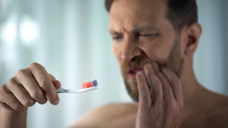 Man holding bloody toothbrush due to gum disease