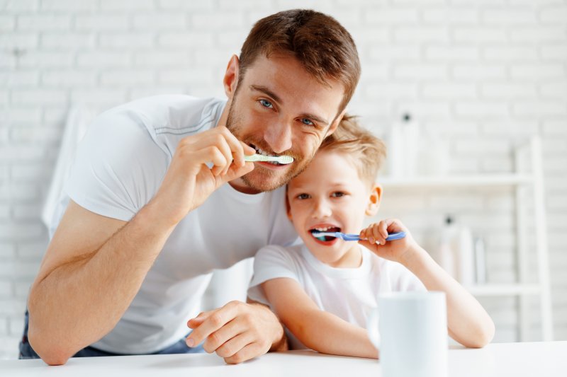 Father and child performing holistic cavity prevention