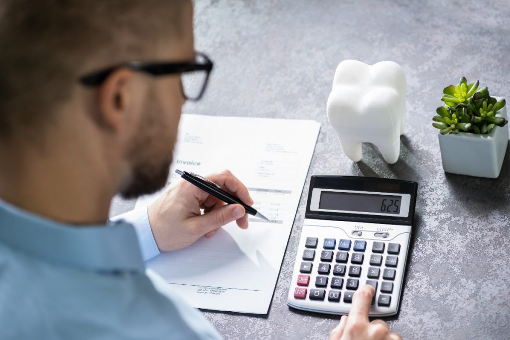 Person holding pen and planning to maximize dental insurance benefits