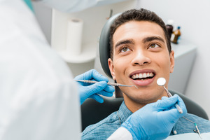 Young man having teeth examined during dental appointment