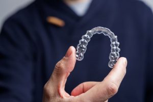 Man using thumb and forefinger to hold Invisalign aligner