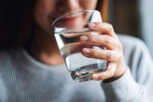 Woman sipping from glass of cool water