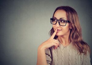 Woman touching her lips, wearing curious expression 